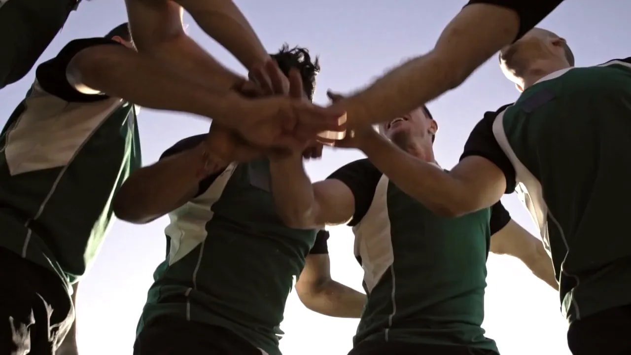 Atletisch team met de handen ineen van onderaf gezien, symboliseert teamwork en eenheid